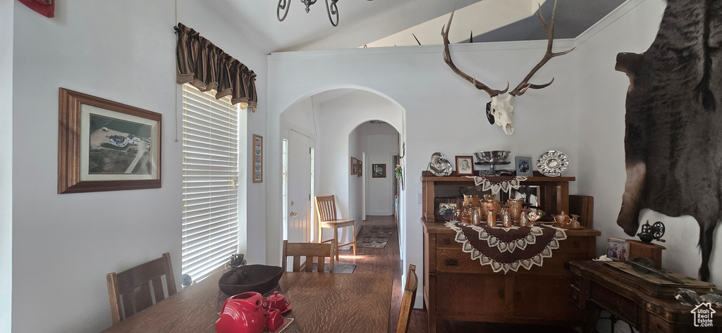 Dining area featuring arched walkways, wood finished floors, a chandelier, and high vaulted ceiling