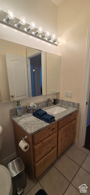 Bathroom with toilet, vanity, and tile patterned floors