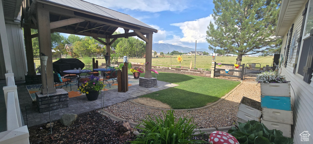 View of grassy yard featuring a gazebo, a mountain view, and a patio