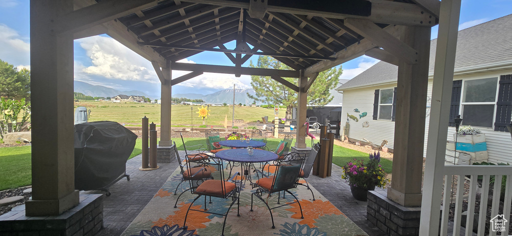 View of patio / terrace with a mountain view, a gazebo, outdoor dining space, and a grill