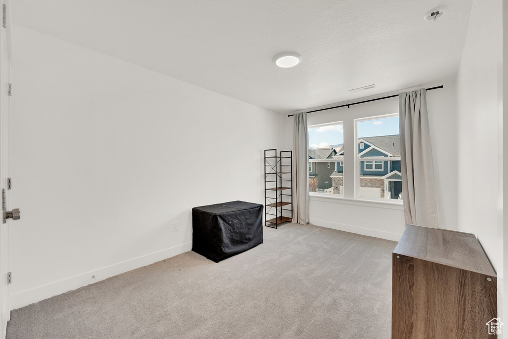 Empty room featuring light colored carpet, baseboards, and fire sprinkler in ceiling