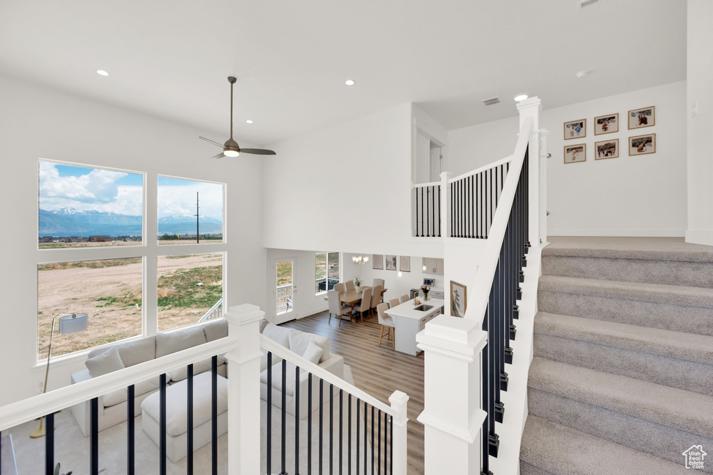 Staircase featuring ceiling fan, wood finished floors, recessed lighting, and a towering ceiling
