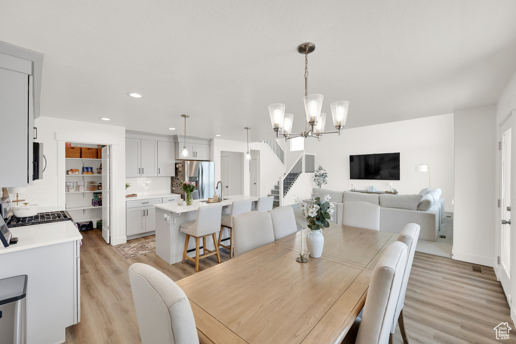 Dining room featuring light wood-style flooring, stairs, recessed lighting, and a chandelier