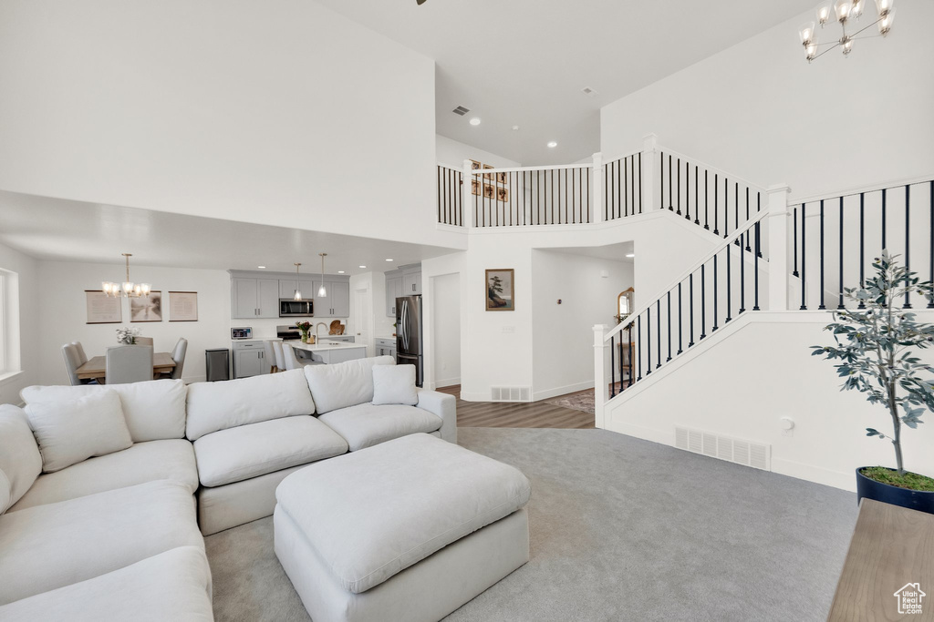 Living area with a chandelier, a towering ceiling, stairway, recessed lighting, and baseboards