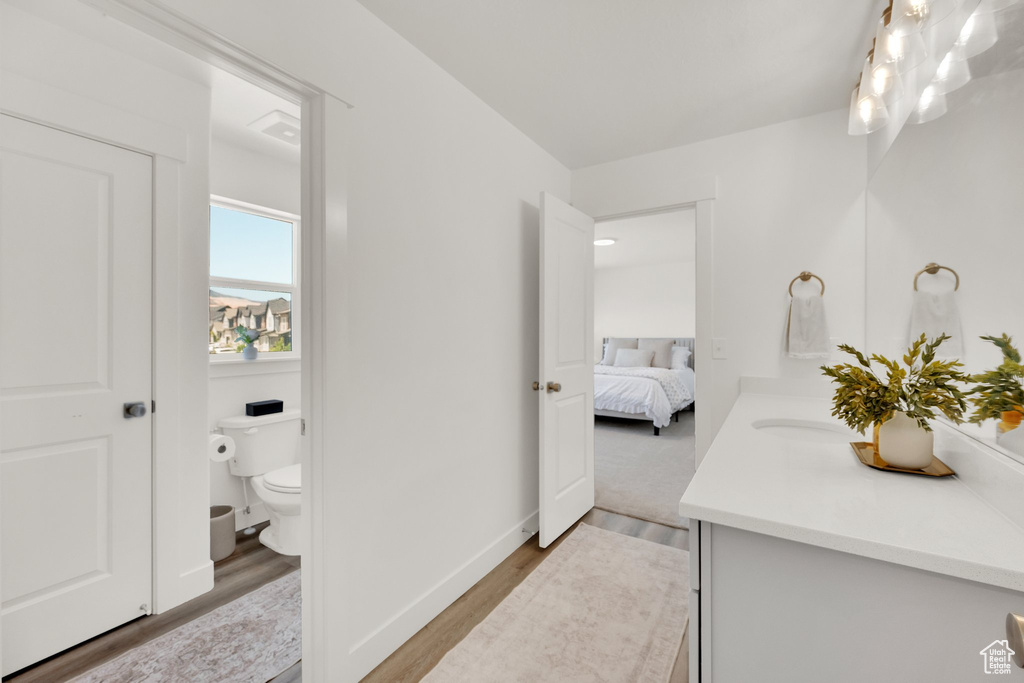 Bathroom with vanity, toilet, wood finished floors, ensuite bath, and baseboards