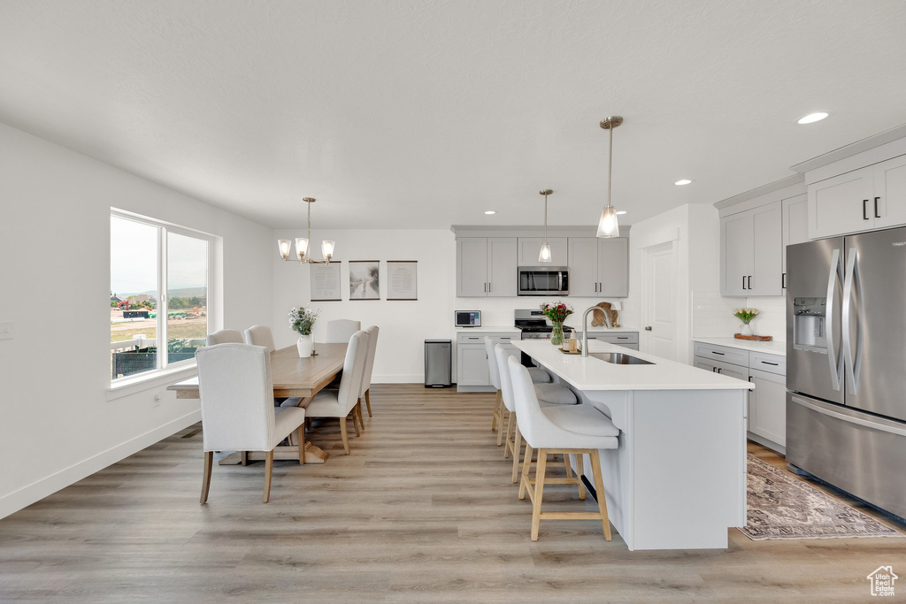 Kitchen with appliances with stainless steel finishes, a sink, light countertops, recessed lighting, and baseboards