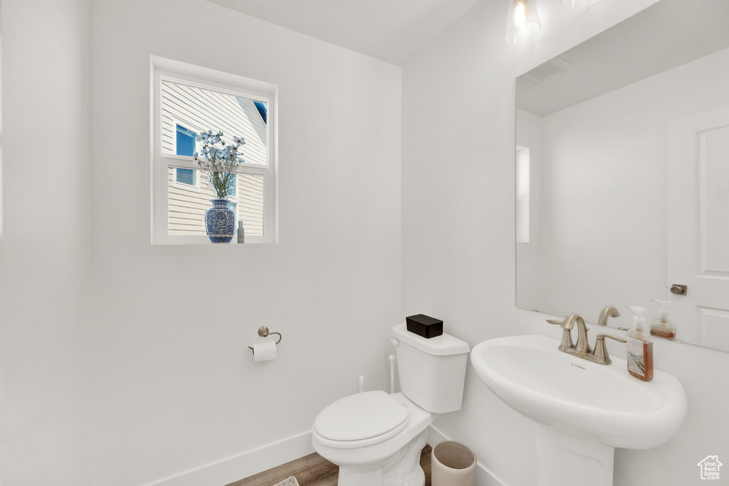 Bathroom with baseboards, toilet, wood finished floors, and a sink