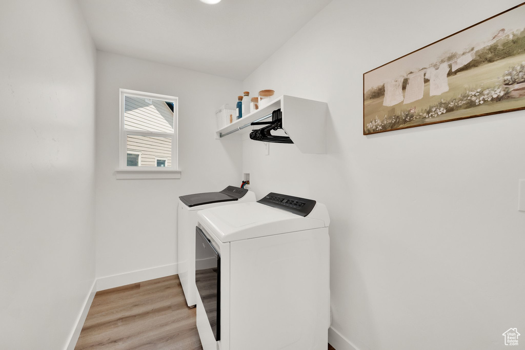 Washroom with independent washer and dryer, light wood-type flooring, and baseboards