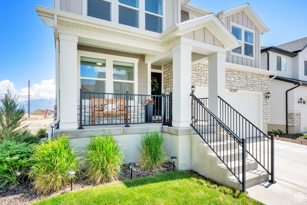 View of front facade with an attached garage, concrete driveway, a porch, stone siding, and board and batten siding