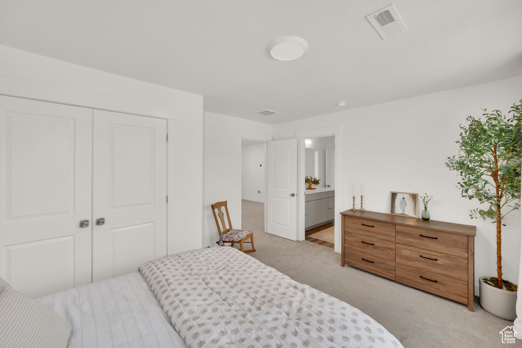 Carpeted bedroom featuring a closet and ensuite bath