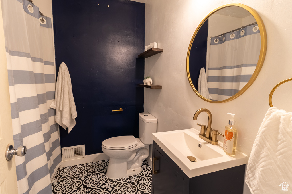 Full bathroom featuring toilet, vanity, tile patterned flooring, and baseboards