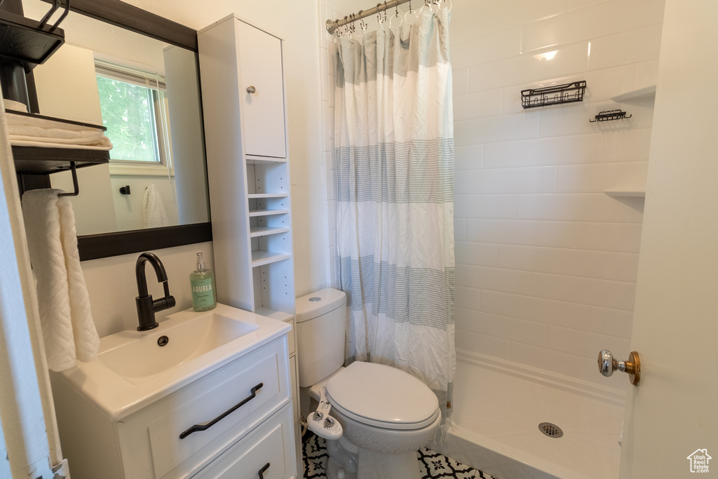 Bathroom with toilet, a shower with shower curtain, and vanity