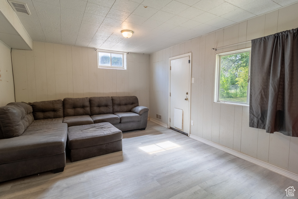 Living area featuring light wood-type flooring, baseboards, and wood walls