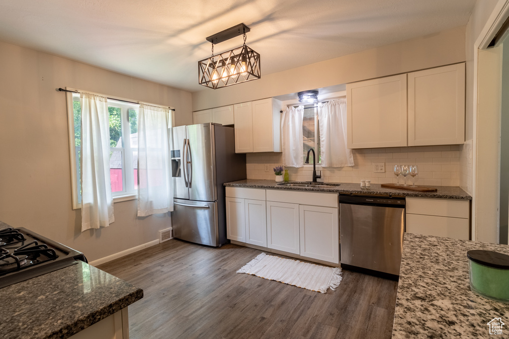 Kitchen featuring stainless steel appliances, a sink, tasteful backsplash, white cabinetry, and dark wood-style flooring