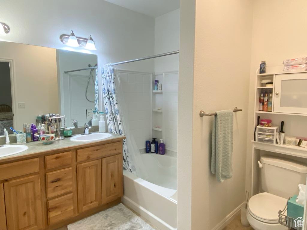 Bathroom with shower / tub combo with curtain, toilet, and double vanity