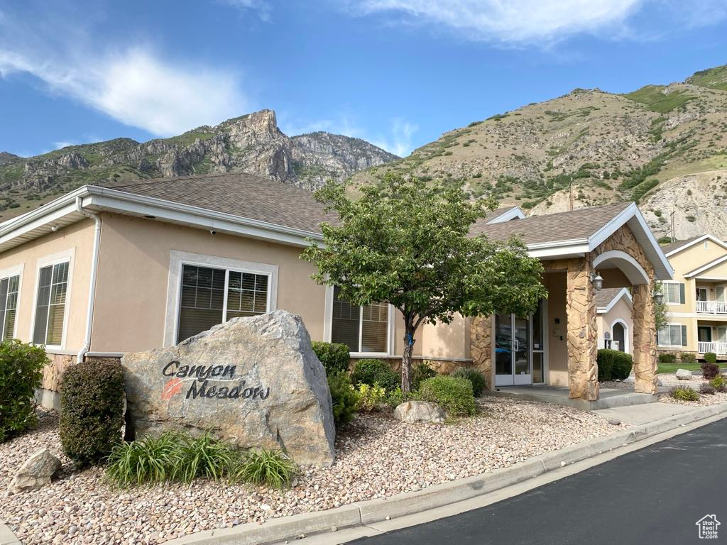 View of front of house with a mountain view, stucco siding, stone siding, and a shingled roof