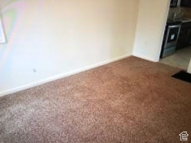 Empty room featuring dark colored carpet and baseboards