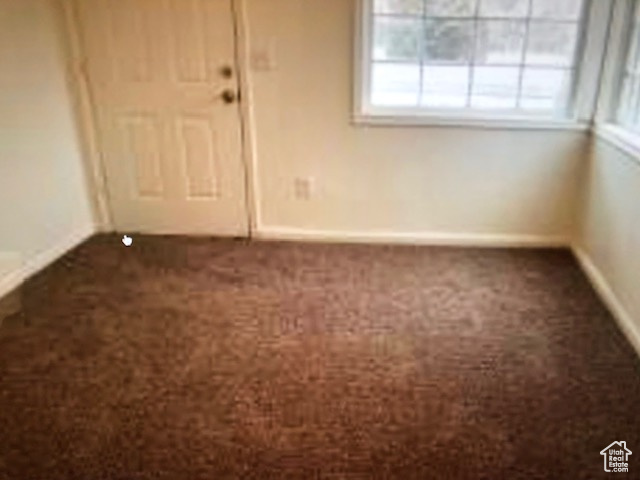 Spare room with dark colored carpet and baseboards