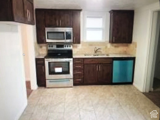 Kitchen with stainless steel appliances, light countertops, a sink, dark brown cabinets, and decorative backsplash