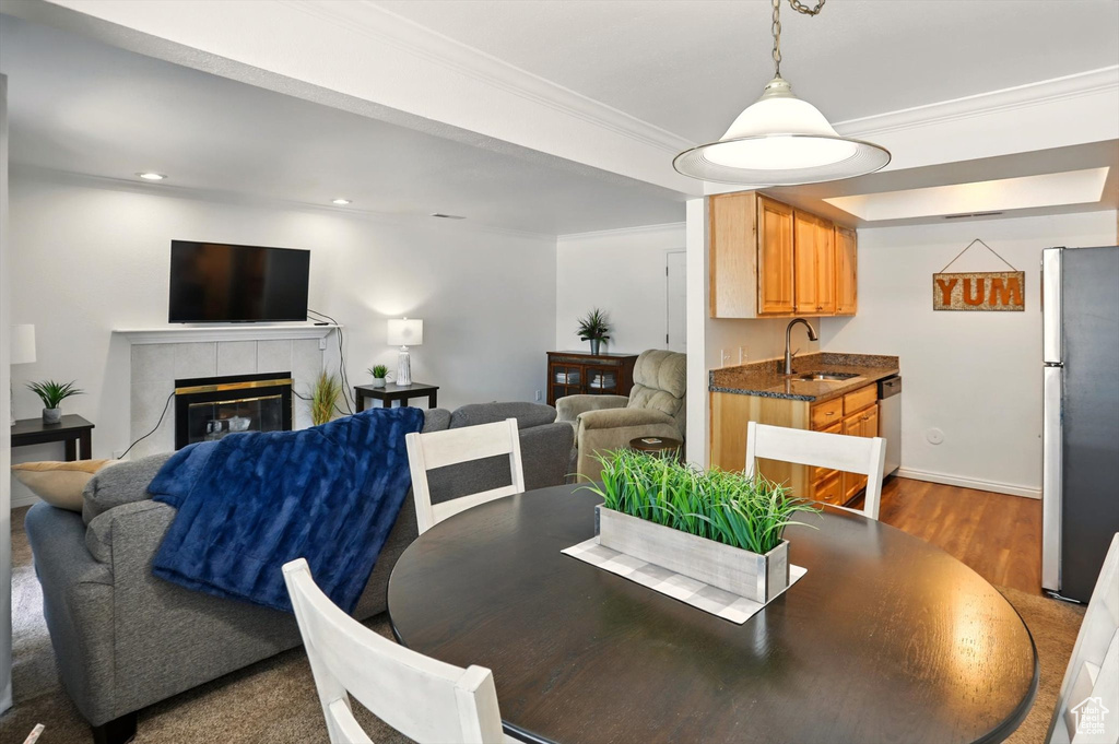 Dining room featuring dark wood-type flooring, a tile fireplace, ornamental molding, recessed lighting, and baseboards