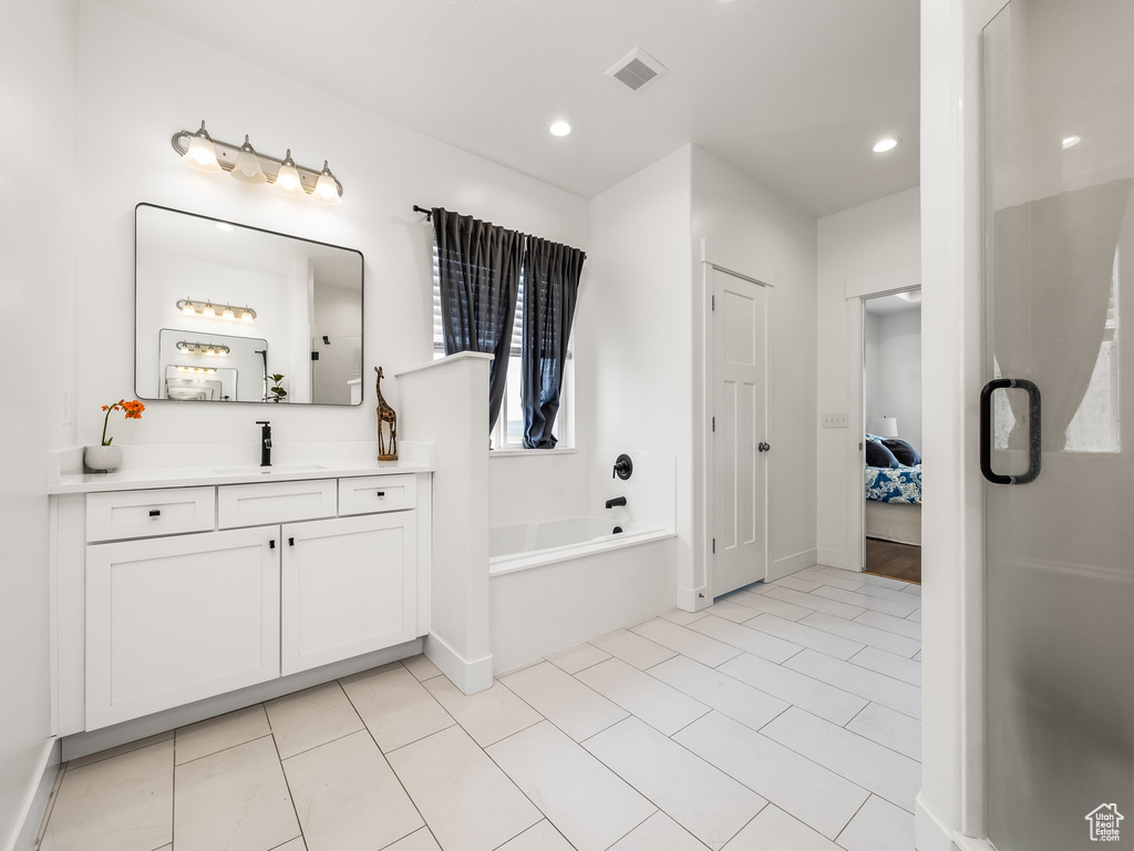 Ensuite bathroom featuring vanity, a bath, recessed lighting, and tile patterned flooring