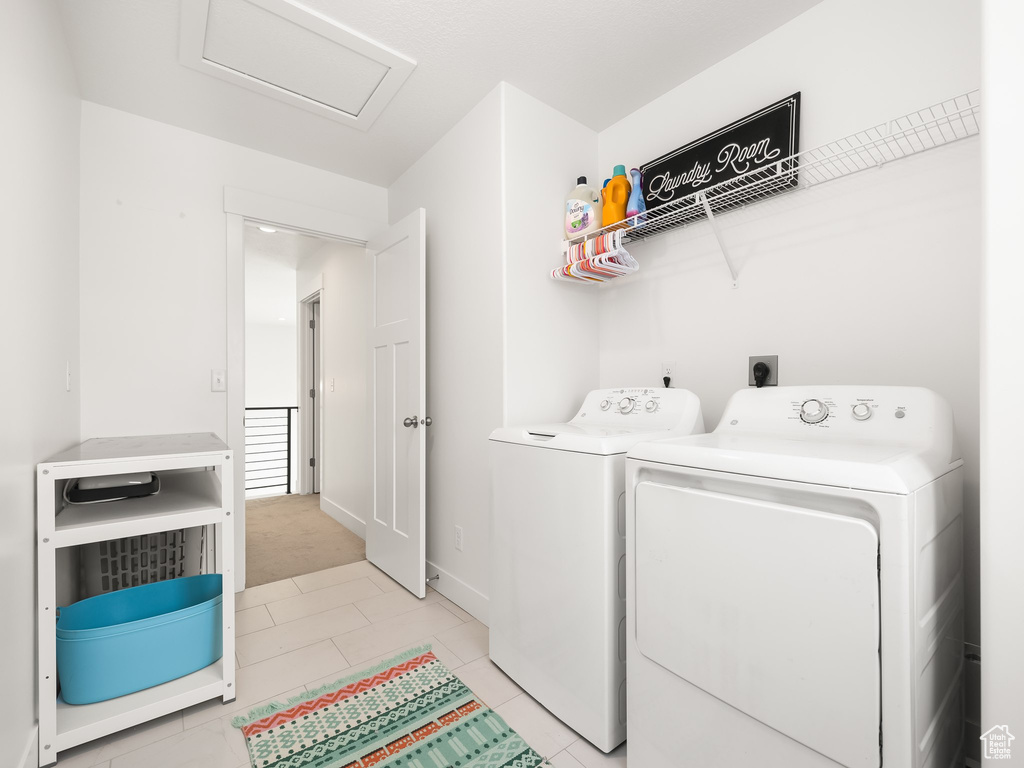 Laundry room with attic access, washing machine and dryer, and light tile patterned flooring