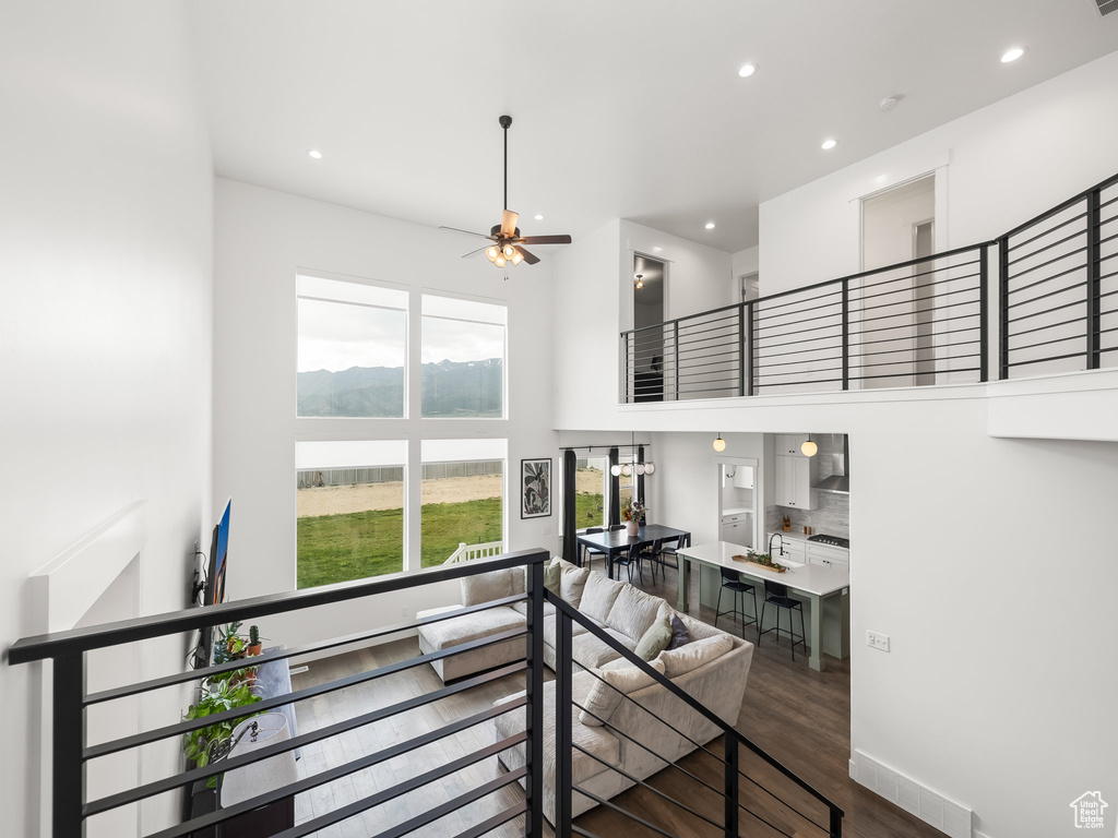 Stairs featuring a towering ceiling, a ceiling fan, recessed lighting, and wood finished floors