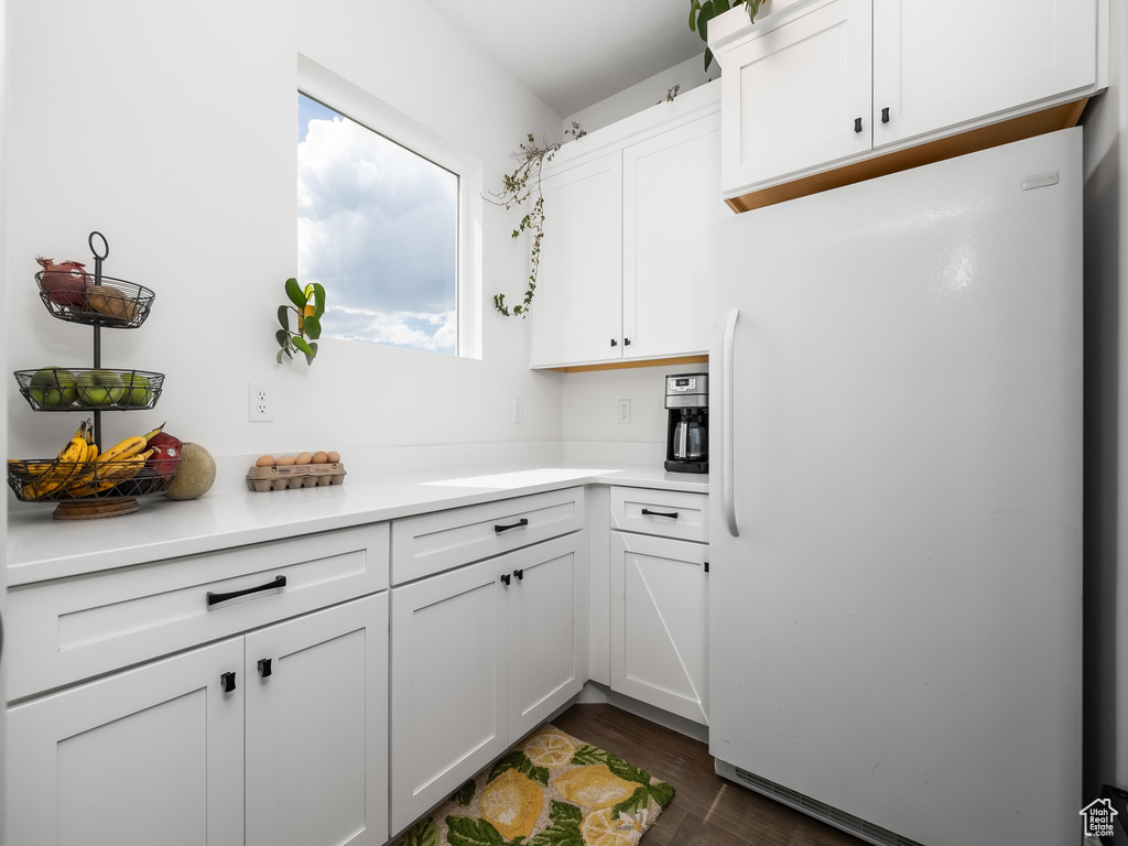 Kitchen with freestanding refrigerator, white cabinets, light countertops, and dark wood-style floors