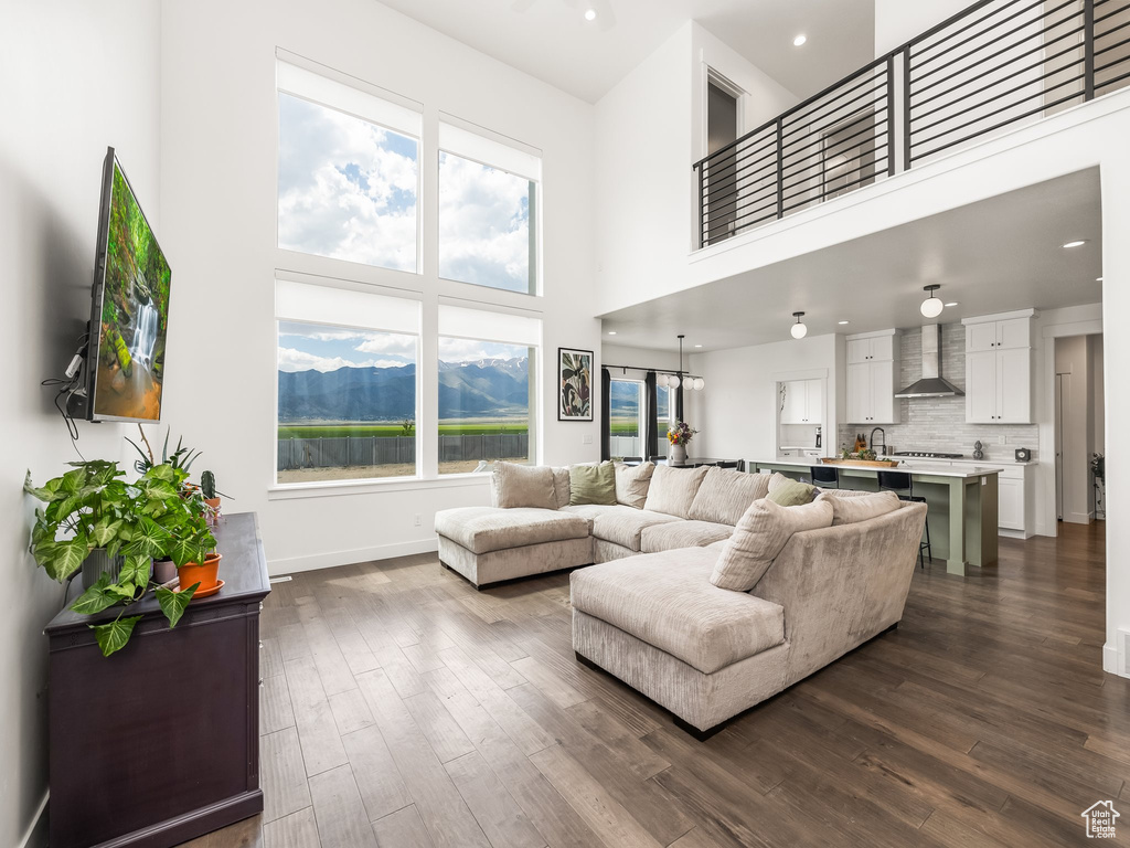 Living area featuring dark wood-type flooring, a high ceiling, baseboards, and recessed lighting