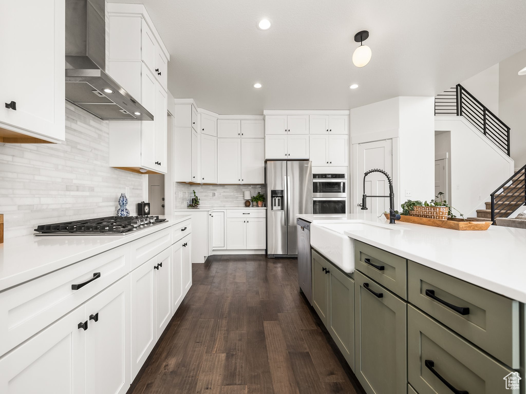Kitchen with wall chimney exhaust hood, appliances with stainless steel finishes, a sink, gray cabinetry, and light countertops