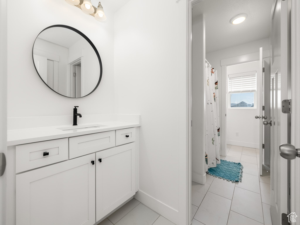 Full bathroom with vanity, baseboards, and tile patterned flooring