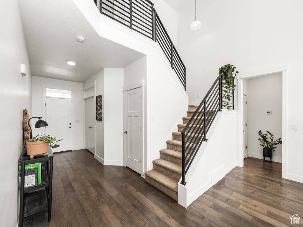 Foyer entrance featuring stairway, dark wood finished floors, baseboards, and a high ceiling