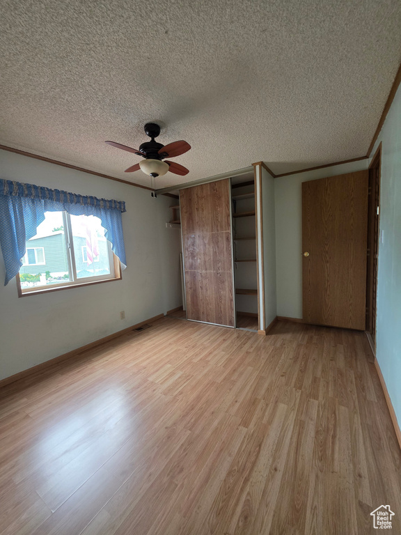 Unfurnished bedroom with light wood finished floors, a textured ceiling, baseboards, and a ceiling fan