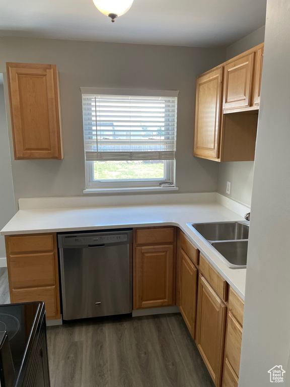 Kitchen with stainless steel dishwasher, a sink, dark wood-type flooring, light countertops, and black electric range