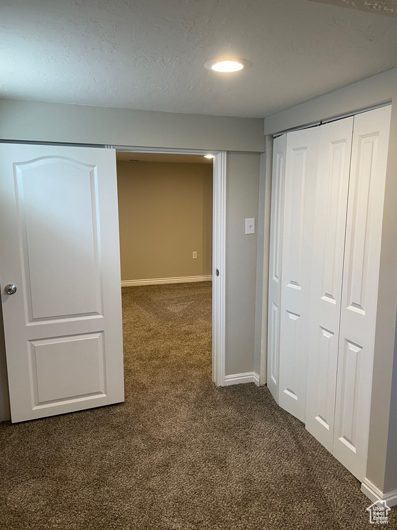 Hallway with dark colored carpet and baseboards