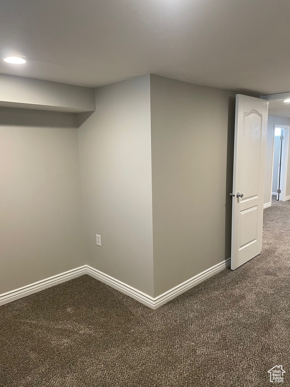 Finished basement with dark carpet and baseboards