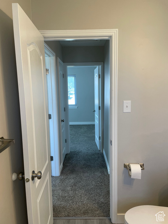 Hallway featuring baseboards and dark carpet