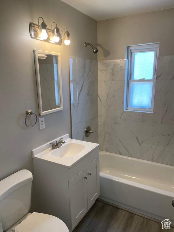 Bathroom with toilet, vanity, bathtub / shower combination, and wood finished floors