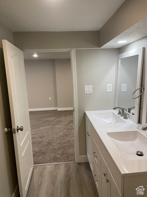 Bathroom with double vanity, wood finished floors, and baseboards