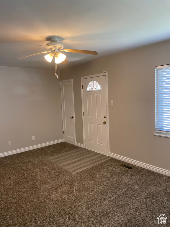 Carpeted foyer with a ceiling fan and baseboards