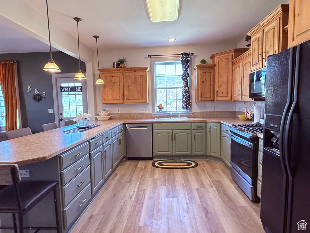 Kitchen featuring black appliances, plenty of natural light, a peninsula, and light countertops