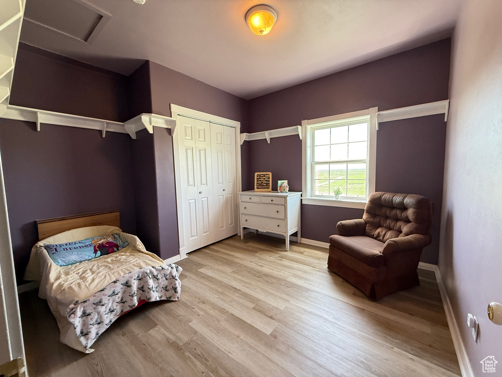 Bedroom with light wood-style floors, baseboards, attic access, and a closet