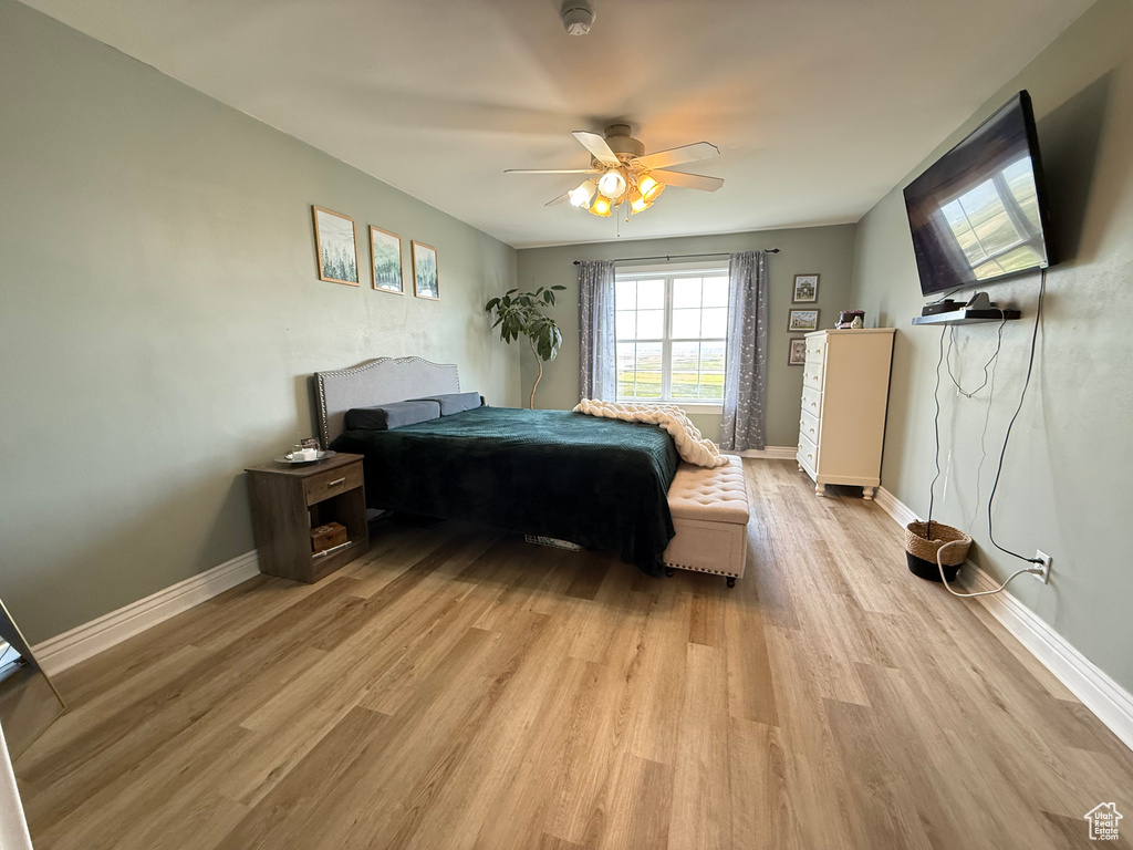Bedroom with light wood-type flooring, baseboards, and ceiling fan
