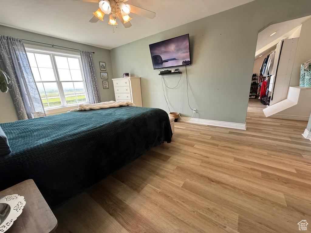 Bedroom featuring baseboards, light wood-style floors, and a ceiling fan