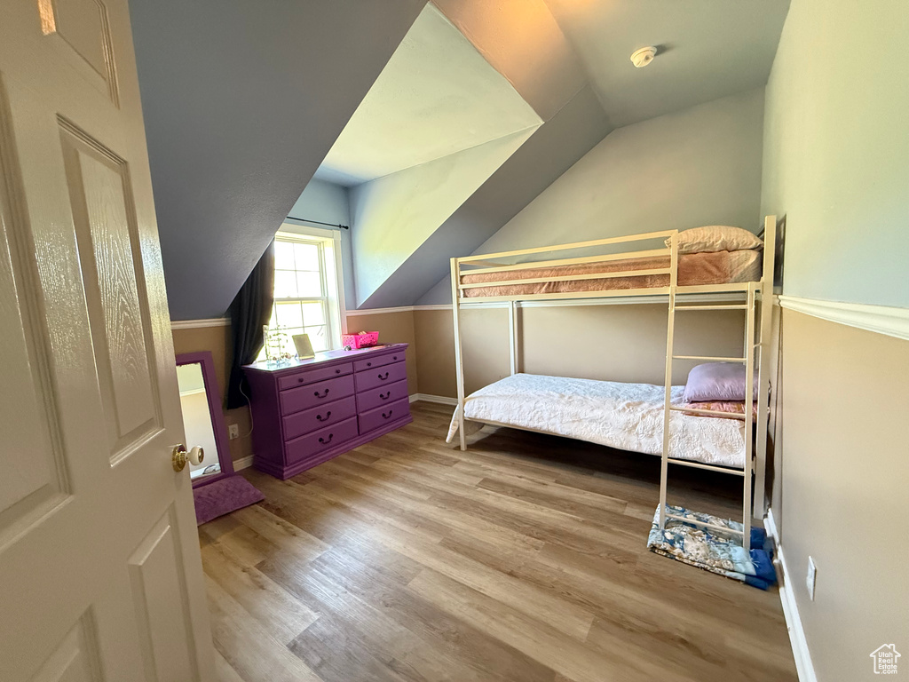 Bedroom featuring lofted ceiling, wood finished floors, and baseboards