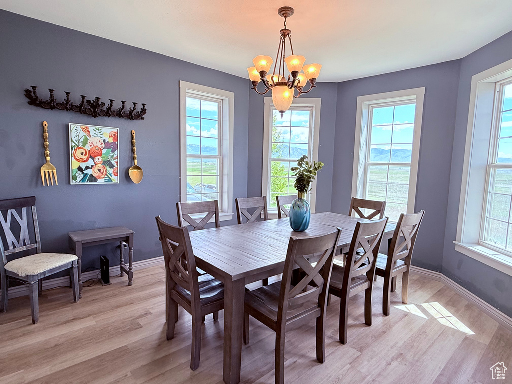Dining space with a chandelier, light wood-style floors, healthy amount of natural light, and baseboards