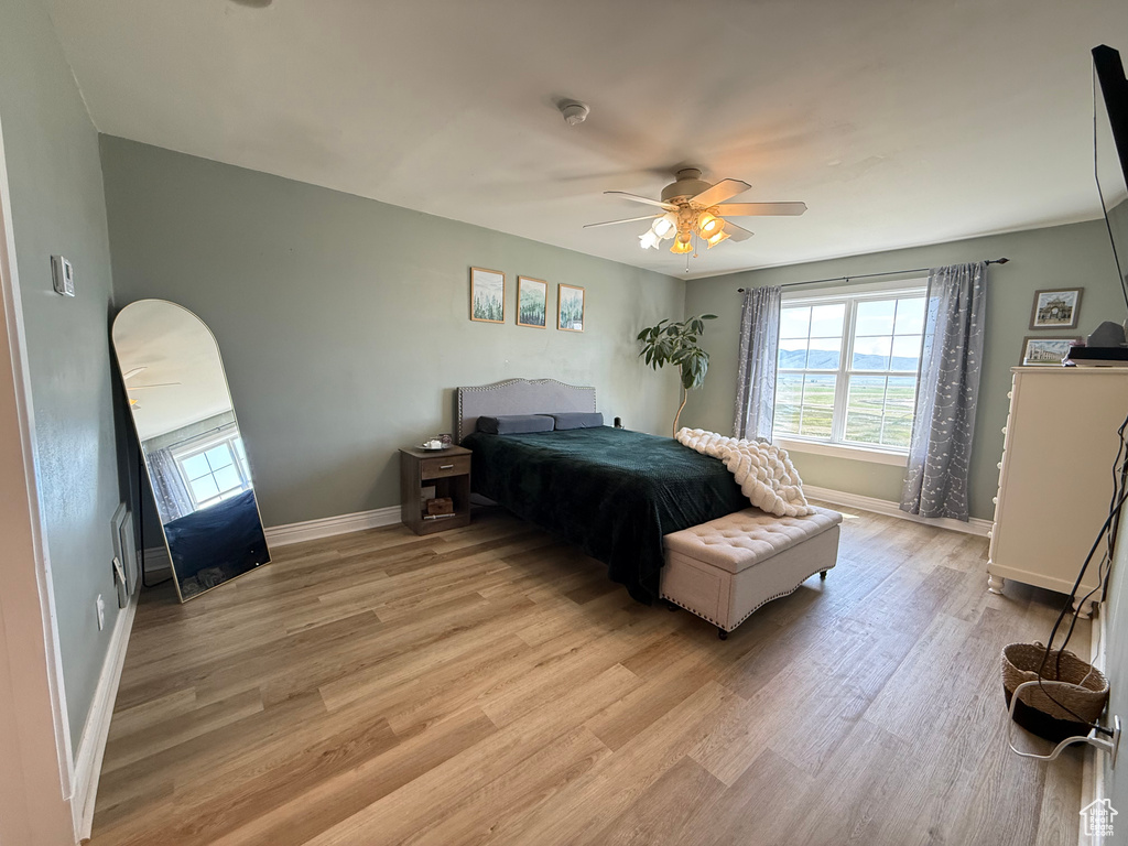 Bedroom featuring light wood-type flooring, multiple windows, and baseboards