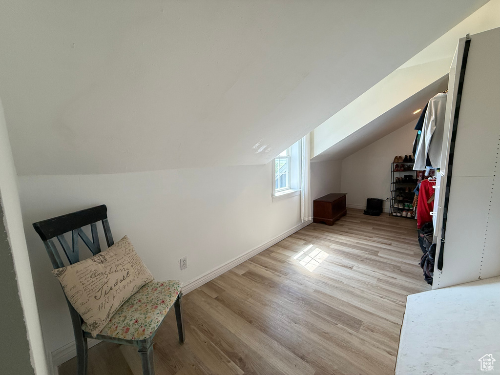 Additional living space featuring light wood finished floors, lofted ceiling, and baseboards