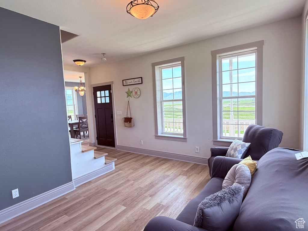 Living room with a chandelier, light wood-style floors, and baseboards