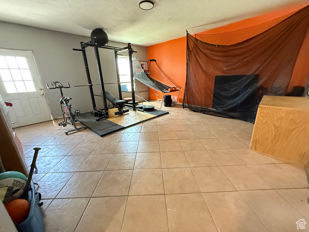 Workout area with healthy amount of natural light, a textured ceiling, and tile patterned floors